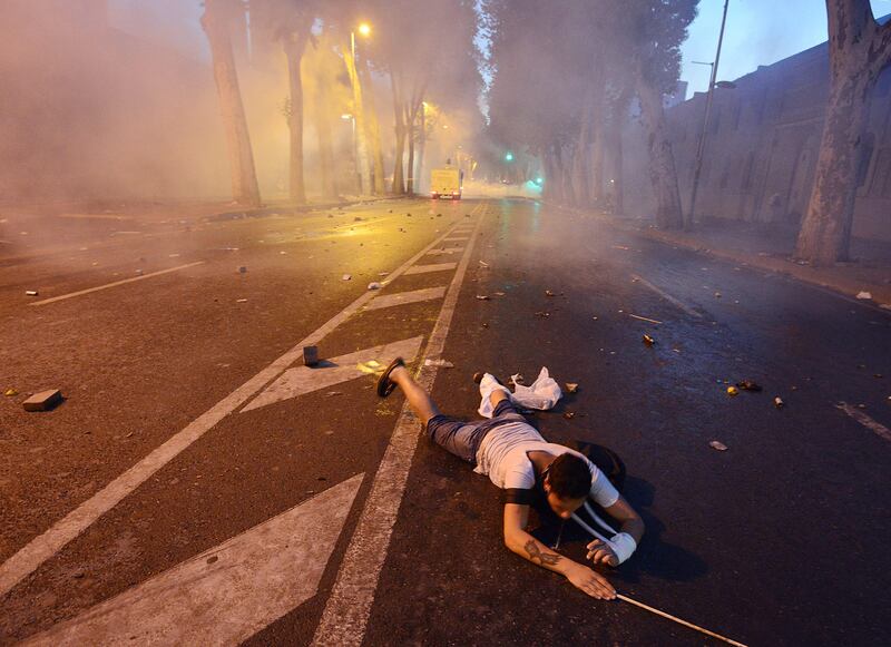 An injured man lies on the ground as Turkish protesters clash with riot police near the former Ottoman palace, Dolmabahce, where Turkey's Prime Minister Recep Tayyip Erdogan maintains an office in Istanbul, Turkey, late Saturday, June 1, 2013. Turkish police retreated from a main Istanbul square Saturday, removing barricades and allowing in thousands of protesters in a move to calm tensions after furious anti-government protests turned the city center into a battlefield. A second day of national protests over a  violent police raid of an anti-development sit-in in Taksim square has revealed the depths of anger against Prime Minister Recep Tayyip Erdogan, who many Turks view as increasingly authoritarian and dismissive of opposing views.(AP Photo)