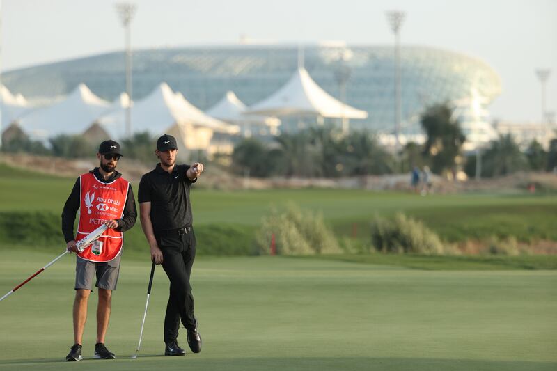 Thomas Pieters lines-up a putt with his caddie Adam Marrow on the 18th green. Getty