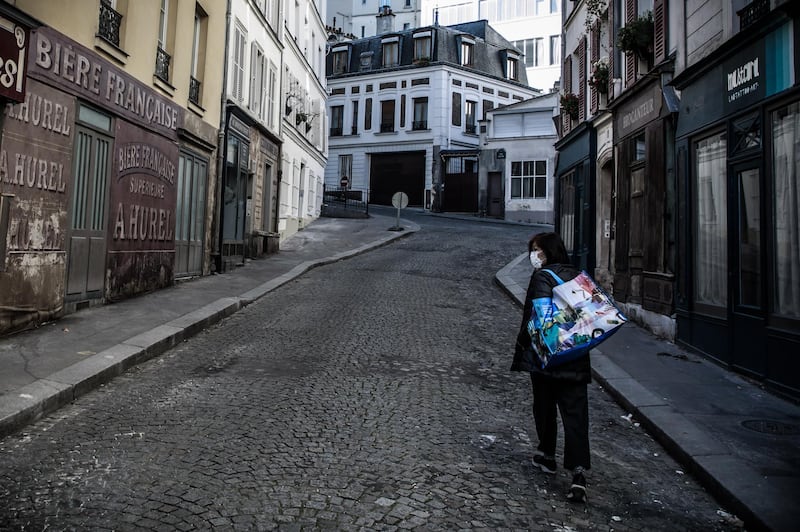 A woman wearing a face mask walks on a deserted street transformed into a movie set, in Paris, France. EPA