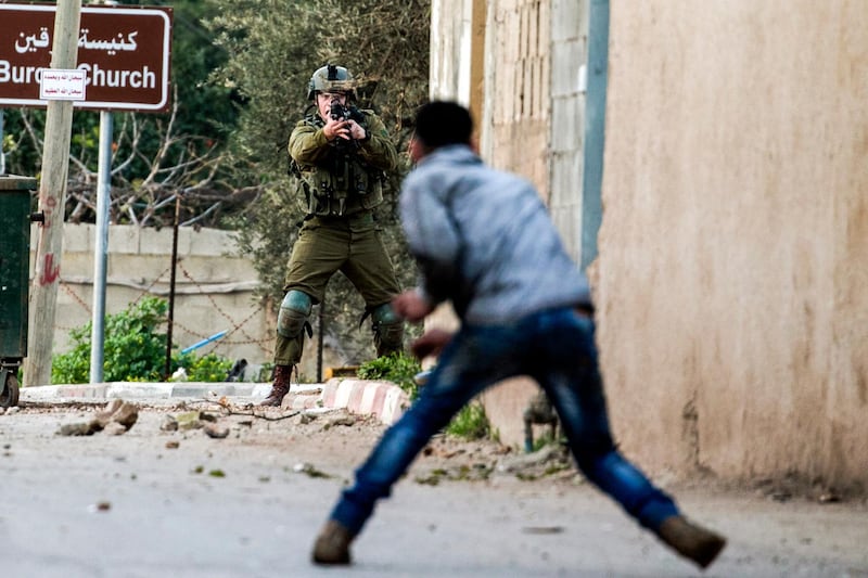 TOPSHOT - A Palestinian protester confronts an Israeli soldier during an army search operation in the Palestinian village of Burqa, about 18 kilometres northwest of Nablus in the occupied West Bank, on February 3, 2018. / AFP PHOTO / JAAFAR ASHTIYEH