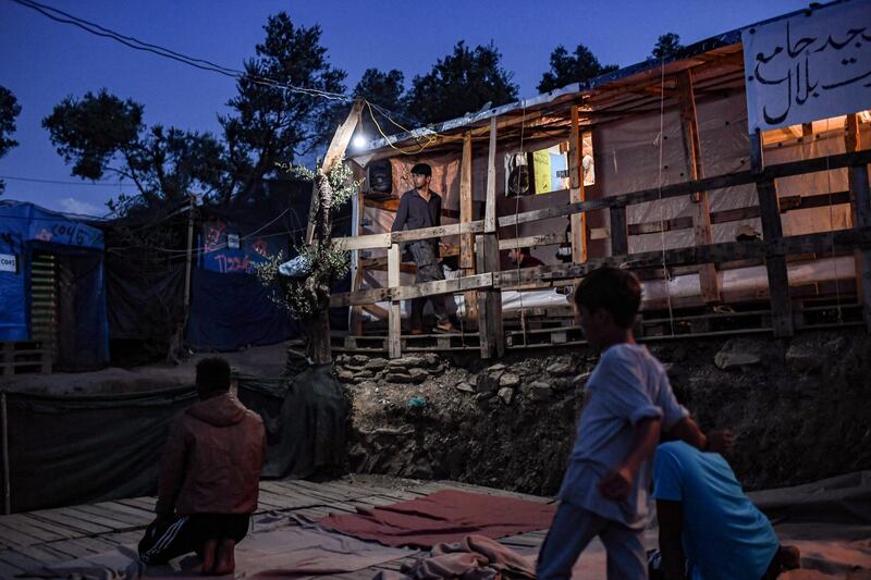 Refugees and migrants are pictured in a improvised tents camp near the refugee camp of Moria in the island of Lesbos on June 21, 2020. - Greece's announcement that it was extending the coronavirus lockdown at its migrant camps until July 5, cancelling plans to lift the measures on June 22, coincided with World Refugee Day on June 27, 2020. (Photo by ARIS MESSINIS / AFP)