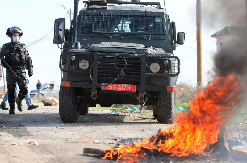 Israeli security members deploy near burning tyres amid clashes with Palestinian protesters in the occupied West Bank.  AFP
