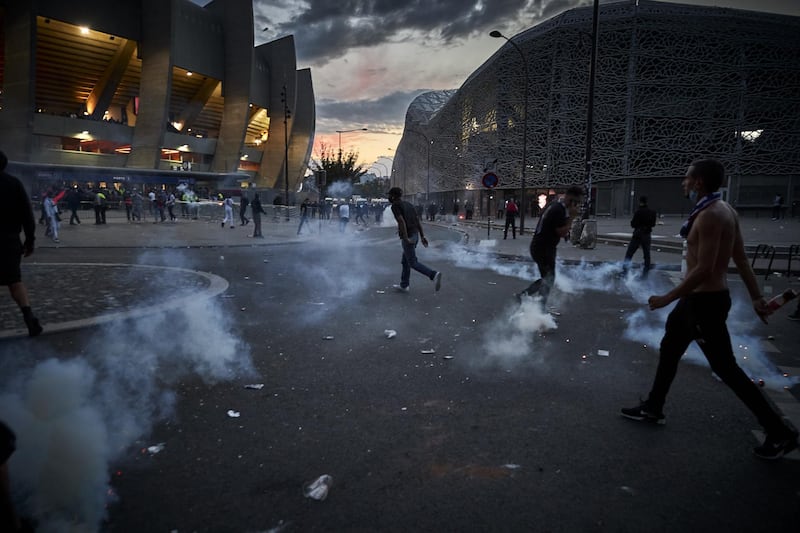 PSG fans run through tear gas during confrontations with police outside Parc de Princes. Getty