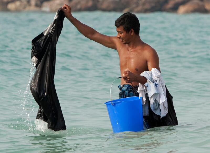 Ajman, August 8, 2011 - Construction worker Jklmn Ro rinses his clothes in the sea off the beach in Ajman City, Ajman, August 8, 2011. (Jeff Topping/The National) 
