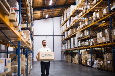 Young male warehouse worker or a supervisor walking with a large box. Courtesy Cartlow