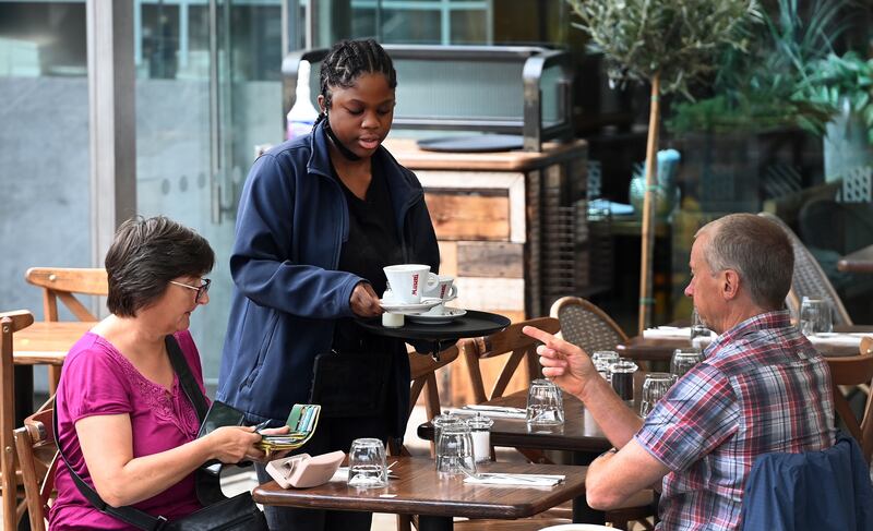 A waitress attends to customers at a restaurant in London. The services sector has struggled to cope with a surge in demand owing to staff shortages. EPA