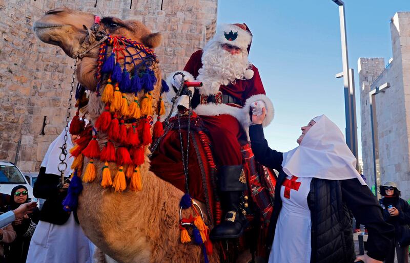 The Jerusalem Santa, a Palestinian dressed up as Father Christmas greets Eastern Orthodox nuns as he rides a camel in Jerusalem's Old City , as Christians around the world prepare to celebrate the holy day.  AFP