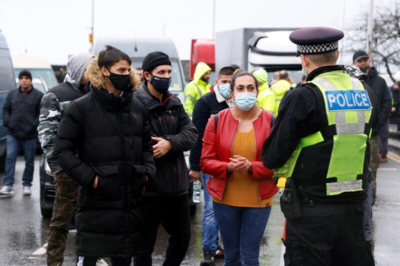 People wearing protective masks talk with a police officer at the entrance of the Port of Dover, as EU countries impose a travel ban from the UK following the coronavirus disease (COVID-19) outbreak, in Dover, Britain.  REUTERS