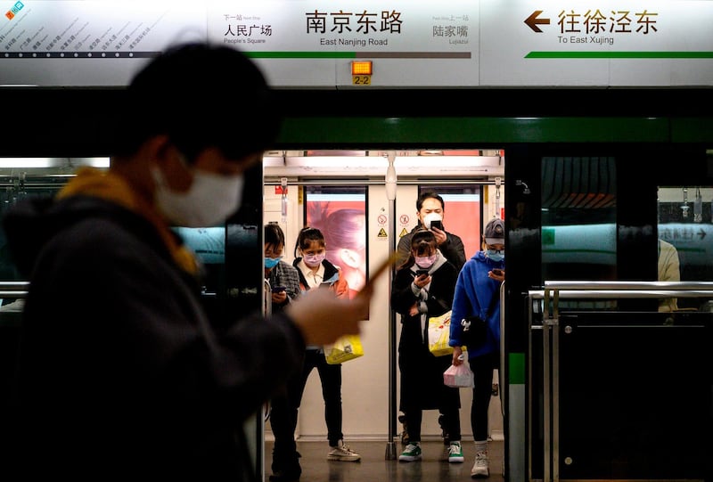 People wearing protective facemasks use their phones on the subway in Shanghai. AFP