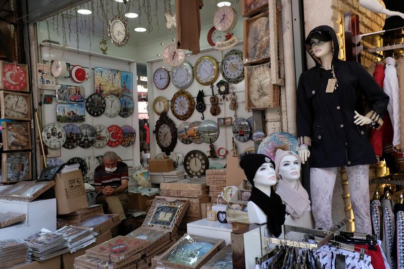 A shopkeeper wearing a protective mask looks at his mobile phone as he waits for customers at Grand Bazaar in Istanbul, Turkey. Reuters