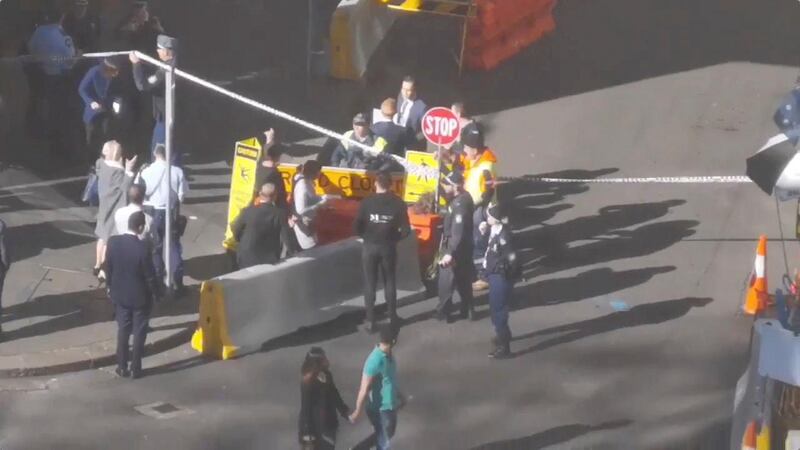 People walk past security officers standing around a barricaded area, following reports of a stabbing incident in the central business district of Sydney, Australia. REUTERS