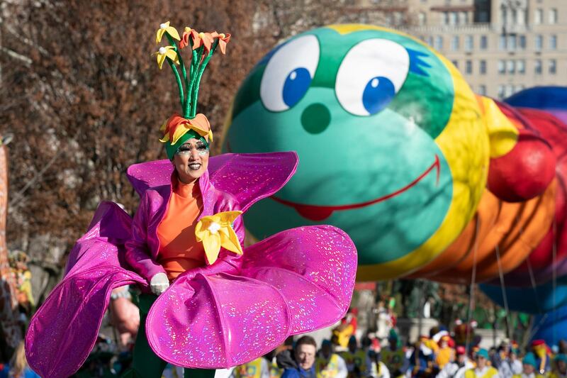 A woman in a flower costume marches in front of the Wiggle Worm balloon during the Macy's Thanksgiving Day Parade in New York.  AP