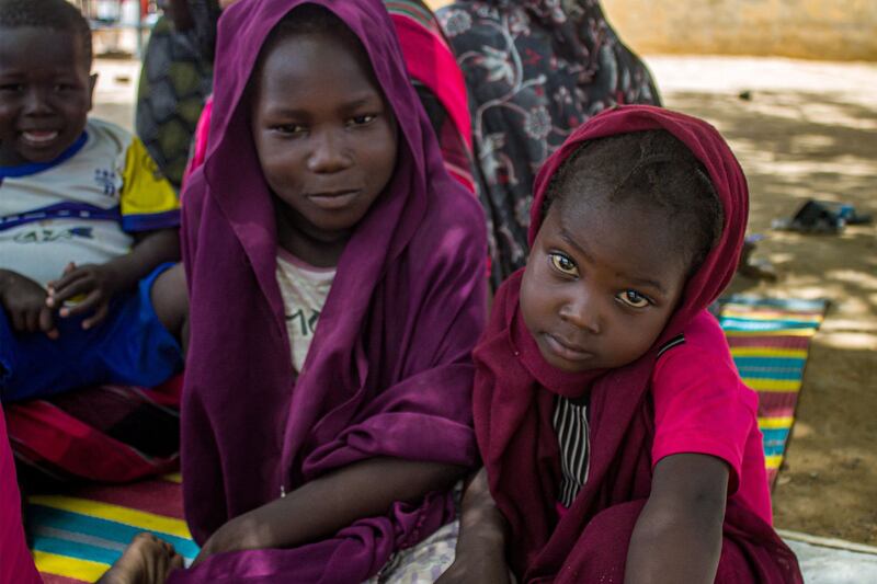 Girls sit outside at a camp for the internally displaced in Al Suwar