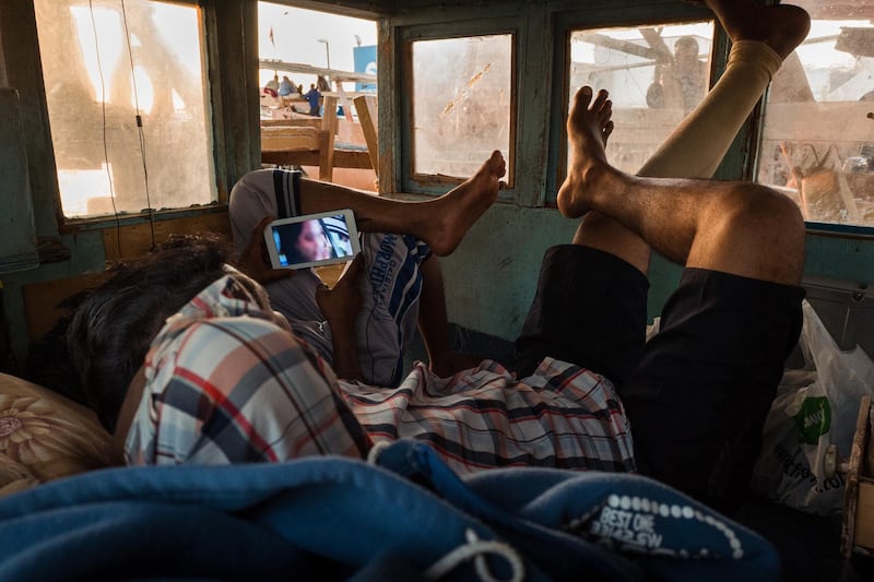 Two men enjoy a Bollywood movie on their smartphone in a cabin at Mina Zayed. Courtesy Sohail Karmani