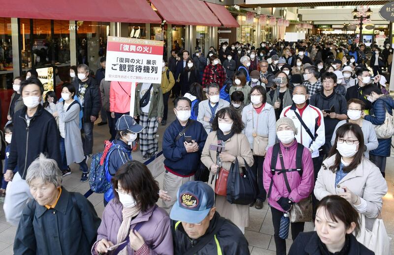 People wearing protective face masks queue as they try to watch the Olympic cauldron during the Tokyo 2020 Olympics Flame of Recovery tour at Sendai Station, Miyagi prefecture, on Saturday. Kyodo/Reuters