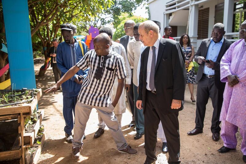 French Foreign Affairs Minister Jean-Yves Le Drian (R) looks on while a Burkinabe entrepreneur explains a project, in Ouagadougou on October 19, 2018 during the inauguration of 'La Ruche' (The Hive), a centre which should serve as a catalyst for interactions between young talents, digital startups and opportunities in French higher education.  / AFP / OLYMPIA DE MAISMONT
