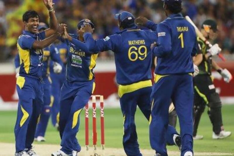 Nuwan Kulasekara of Sri Lanka, left, celebrates with teammates after taking the wicket of David Warner of Australia, right, during the second T20 international against Australia on Monday.