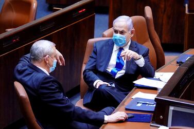 Israeli Prime Minister Benjamin Netanyahu and Benny Gantz, centrist Blue and White leader, and Mr Netanyahu's partner in his new unity government, wear face masks as they talk during a swearing in ceremony of the new government, at the Knesset, Israel's parliament, in Jerusalem May 17, 2020. Reuters