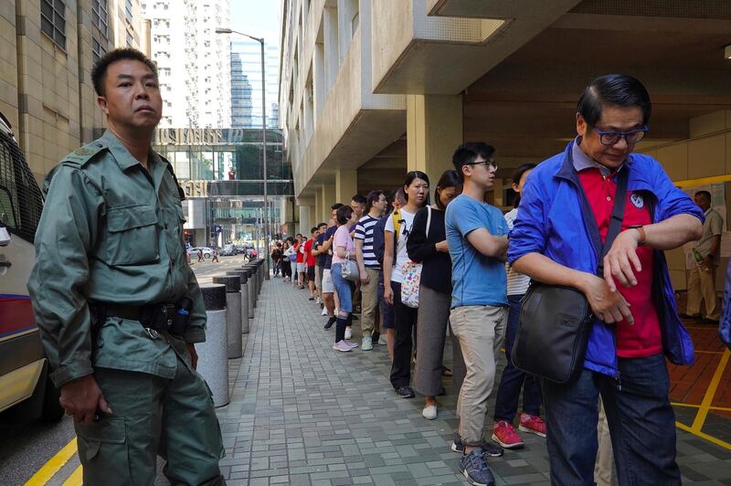 A Hong Kong policeman watches as people line up to vote outside a polling centre. AP Photo