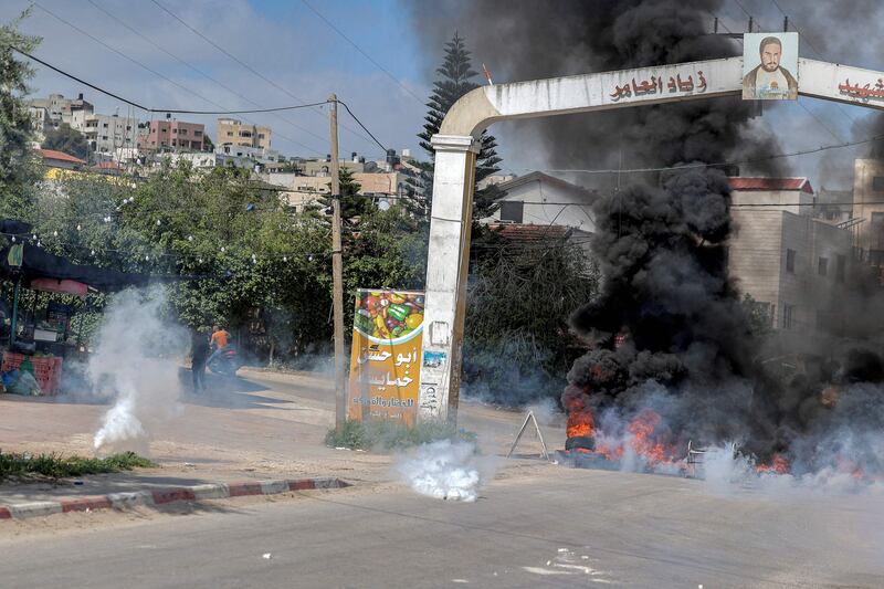 Tear gas canisters fall near flaming tyres by the camp’s entrance. AFP