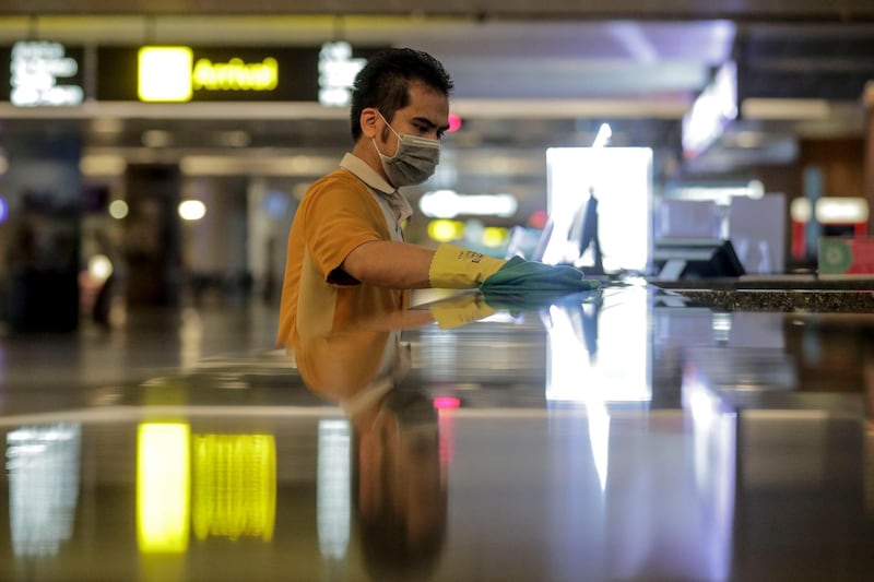 A cleaner wearing a mask wipes a counter top in the arrival hall of Changi Airport's Terminal 2 in Singapore. Changi Airport will close its Terminal 2 for 18 months.  EPA