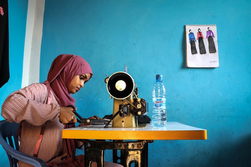 (FILES) In this file photograph taken on November 3, 2018, Hawa Adan Hassan, 23 year-old, university student, uses a sewing machine at her home in Mogadishu, Somalia. Somalia's clothes business is a simple one: foreign imported garments for the well-to-do, locally tailored clothes for the rest. But new fashion designers are complicating that picture with locally-designed, hand-made attire. / AFP / Abdi HAJJI HUSSEIN
