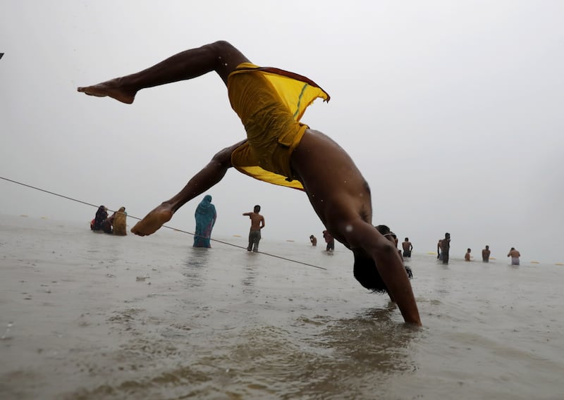An Indian devotee performs yoga as he takes a holy dip. EPA