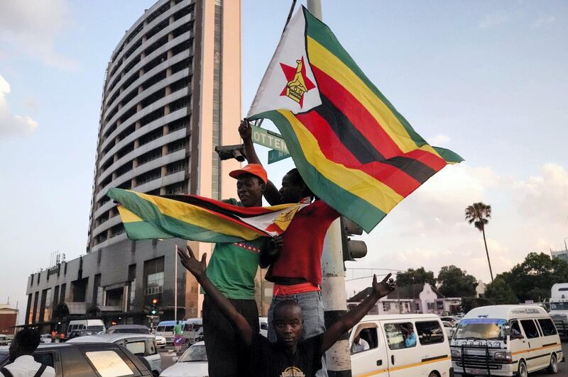 People holding Zimbabwean flags celebrate in the street after the resignation of Zimbabwe's president Robert Mugabe on November 21, 2017 in Harare.
Car horns blared and cheering crowds raced through the streets of the Zimbabwean capital Harare as news spread that President Robert Mugabe, 93, had resigned after 37 years in power. / AFP PHOTO / Marco Longari