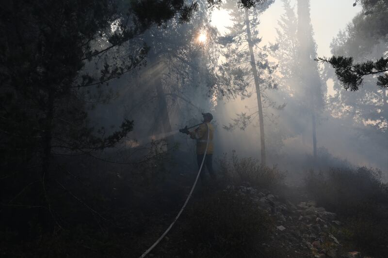 An Israeli firefighter combats the fire near Kibbutz Tzuba, Israel.
