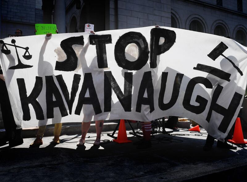 Demonstrators hold anti-Kavanaugh hold a banner outside City Hall in Los Angeles on September 28, 2018.  The Senate Judiciary Committee on Friday approved Brett Kavanaugh, Donald Trump's pick for the US Supreme Court, one day after he fought off allegations of sexual assault at an emotional day-long public hearing. But in a dramatic last-minute move, Republican Senator Jeff Flake of Arizona asked for a delay of up to a week before the full vote takes place to allow for an FBI investigation into the allegations against Kavanaugh. / AFP / Mark RALSTON
