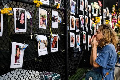TOPSHOT - A woman prays in front of photos at the makeshift memorial for the victims of the building collapse, near the site of the accident in Surfside, Florida, north of Miami Beach on June 27, 2021. The death toll after the collapse of a Florida apartment tower has risen to nine, officials said Sunday, with more than 150 people still missing and their weary families waiting more than three days afterwards for information as to their fate.
The outlook grew more and more grim by the hour, however, as the slow rescue operation, involving workers sorting nonstop through the rubble in torrid heat and high humidity, carried on.
 / AFP / CHANDAN KHANNA
