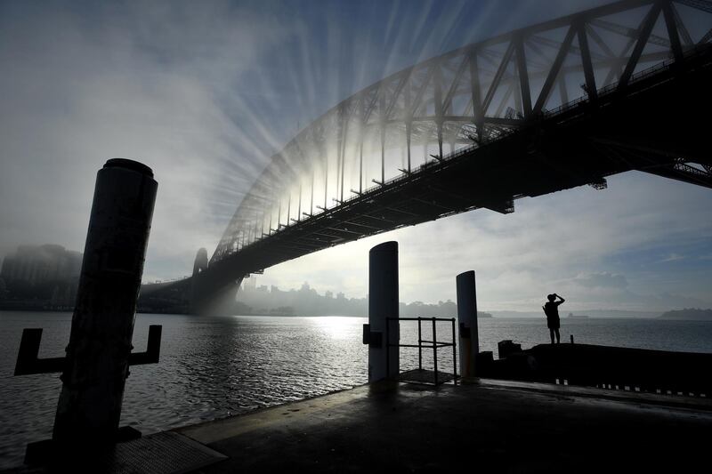 The sun rises behind Sydney Harbour Bridge, with the light diffused by early morning fog and haze, in Sydney, Australia. EPA