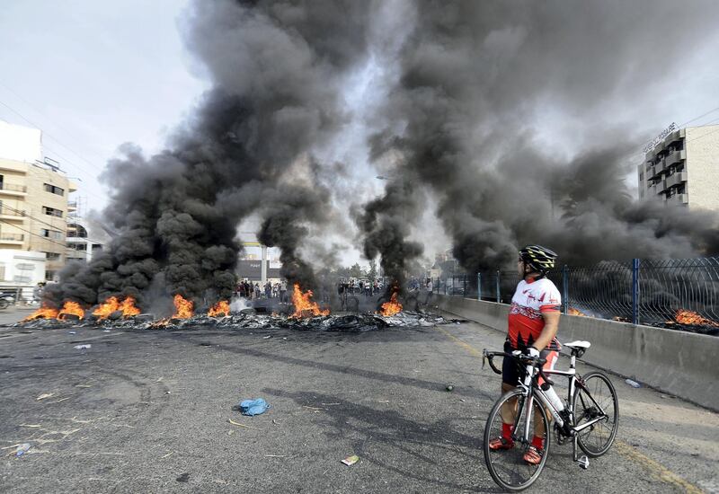 Lebanese demonstrators burn tires during a protest against dire economic conditions, on October 18, 2019 on a highway between the capital Beirut and the northern city of Tripoli. - The Lebanese government faced calls to resign after thousands of furious demonstrators took to the streets across the country to protest dire economic conditions. Public anger has simmered since parliament passed an austerity budget in July to help trim a ballooning deficit and flared on Thursday over plans to tax calls on messaging applications, forcing the government to axe the unpopular measure (Photo by JOSEPH EID / AFP)