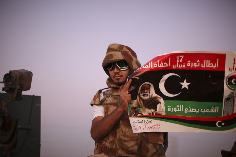 A rebel fighter poses with a pre-Qaddafi flag on the front line in Bani Walid in 2011. The intervention in Libya is often used as a warning against intervention in Syria (AP Photo/Alexandre Meneghini)