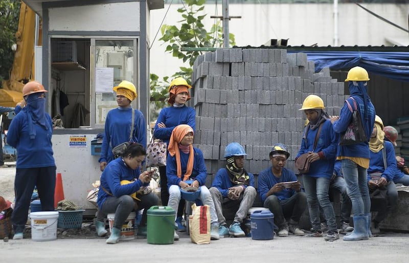 Cambodian migrant construction workers waiting for their transport home outside a building site in downtown Bangkok, Thailand. The International Labor Organization says women make up almost 40 per cent of migrant construction workers in Thailand, more than almost anywhere else in the world. Dake Kang/AP Photo