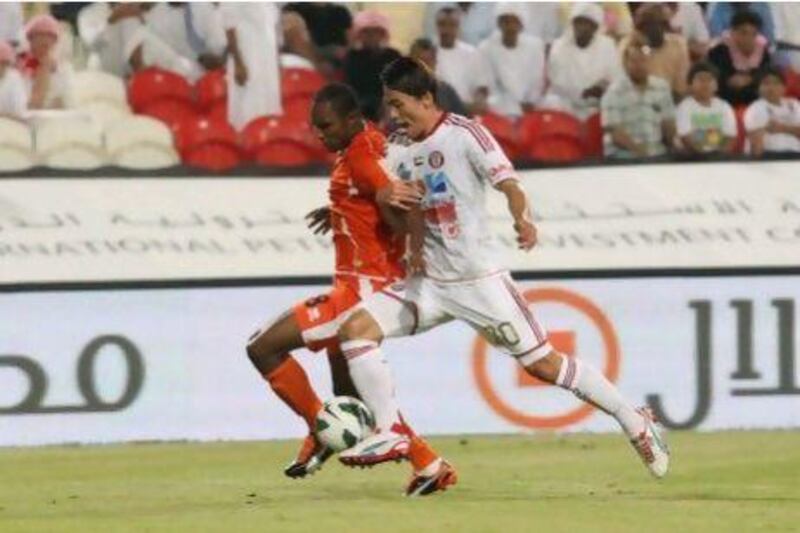 Hyungmin Shin, right, the Al Jazira defender, tussles with Ajman striker Boris Kabi during last night's match. Jaime Puebla / The National