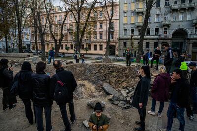 Onlookers at a rocket crater in a park in central Kyiv on Wednesday, days after the site was attacked by Russia. AFP

