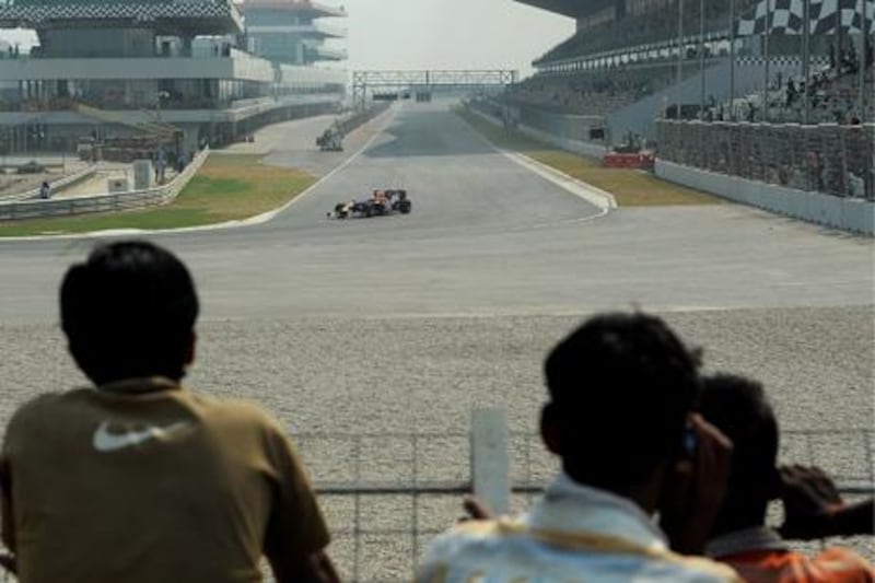 TO GO WITH Auto-Prix-IND-India,FOCUS by Kuldip Lal

(FILES) This file photo taken on October 18, 2011 shows Indian construction workers looking on as a Red Bull Renault Formula One show car drives on the newly-inaugurated Buddh International Circuit ahead of the Indian Grand Prix in Greater Noida, some 60 kms from New Delhi.  If India can pull off a successful Grand Prix on October 30, 2011, the winning driver will not be the only person celebrating a major victory.  The country's inaugural Formula One race, being held at a new track outside the capital New Delhi, is seen as a key test of India's ability to organise and deliver international sporting events.     AFP PHOTO / FILES / MANAN VATSYAYANA

