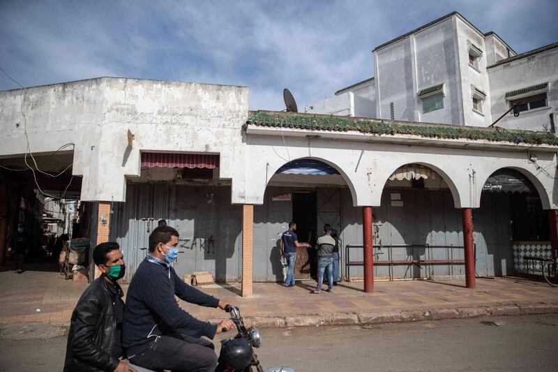 People wearing a face mask drive past empty shops during a state of emergency in Rabat, Morocco. AP