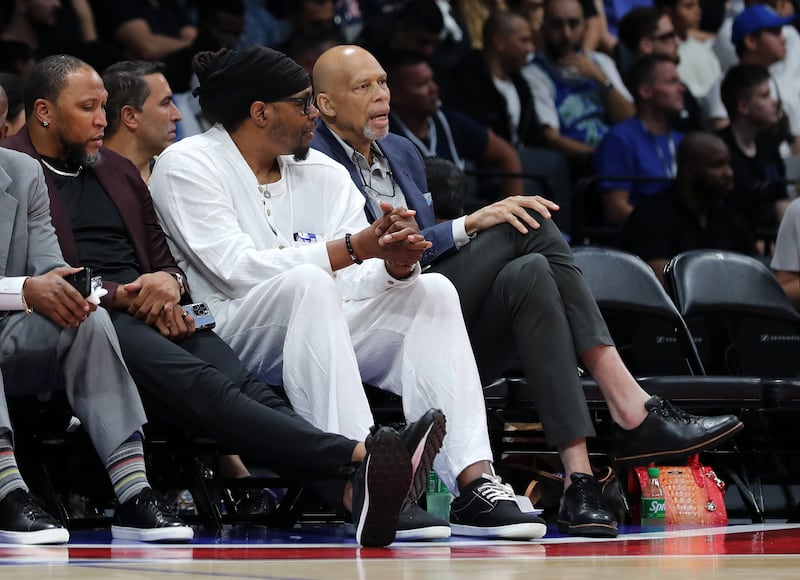 Former NBA players Kareem Abdul-Jabbar, right, and Sam Perkins chat during the game.