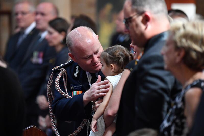 Rural Fire Service Commissioner Shane Fitzsimmons talks to Charlotte O'Dwyer, daughter of NSW RFS volunteer Andrew O'Dwyer, during her father's funeral at Our Lady of Victories Catholic Church in Horsley Park, Sydney.  EPA