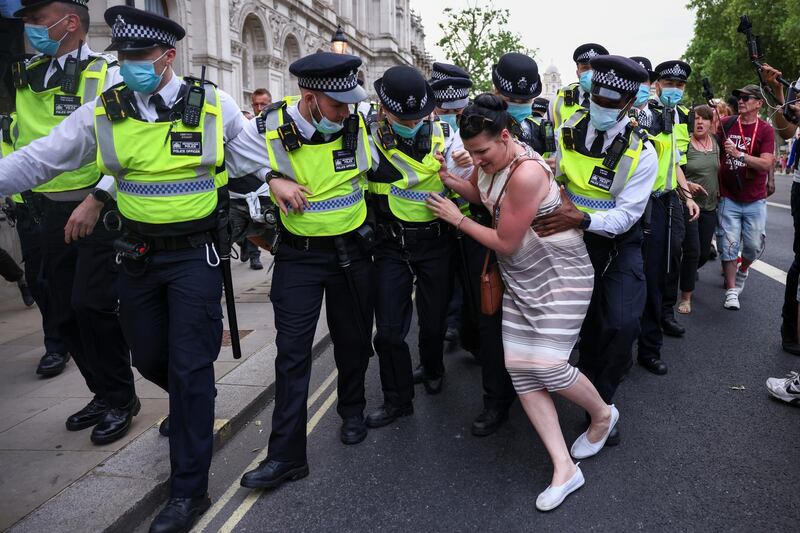 A woman attempts to obstruct police officers from apprehending a demonstrator during an anti-lockdown and anti-vaccine protest in London. Reuters