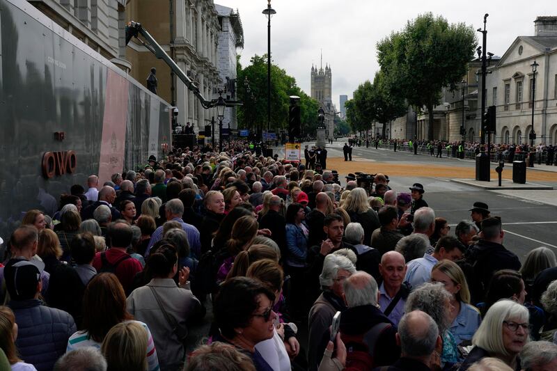 Crowds await the procession of the coffin of Queen Elizabeth II from Buckingham Palace to Westminster Hall, in London.  The queen, Britain's longest-reigning monarch and a rock of stability across much of a turbulent century, died on September 8, 2022, after 70 years on the throne. AP