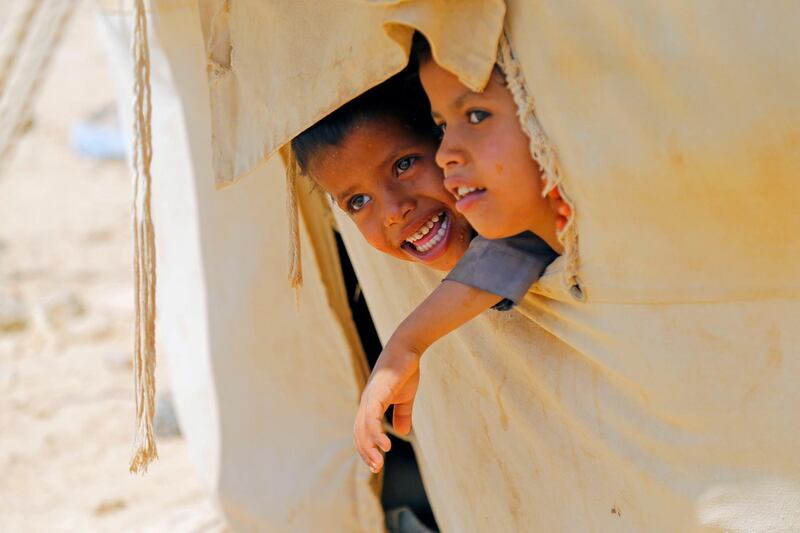 Children look out of their family's tent at a camp for internally displaced people in Marib, Yemen. Reuters