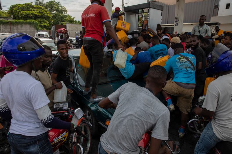 People try to get containers filled at a petrol station, amid chaotic scenes in Port-au-Prince, Haiti. AP Photo
