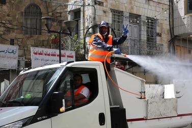 Palestinian municipality staff spray disinfectant in the West Bank town of Hebron, 24 March 2020. EPA