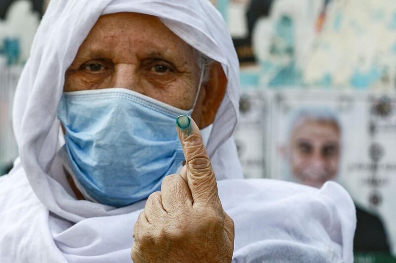 A voter, mask-clad due to Covid-19, shows an ink-stained finger after voting outside a polling station at Al Baqaa camp for Palestinian refugees north of Amman. AFP