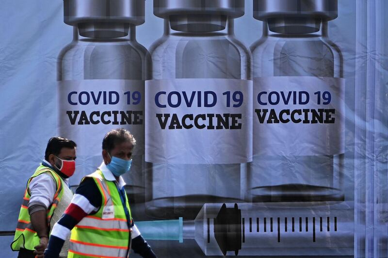 Members of ground staff walk past a container stacked at the Cargo Terminal 2 of the Indira Gandhi International Airport, which will be used as a Covid-19 coronavirus vaccines handling and distribution centre during the media preview in New Delhi. AFP