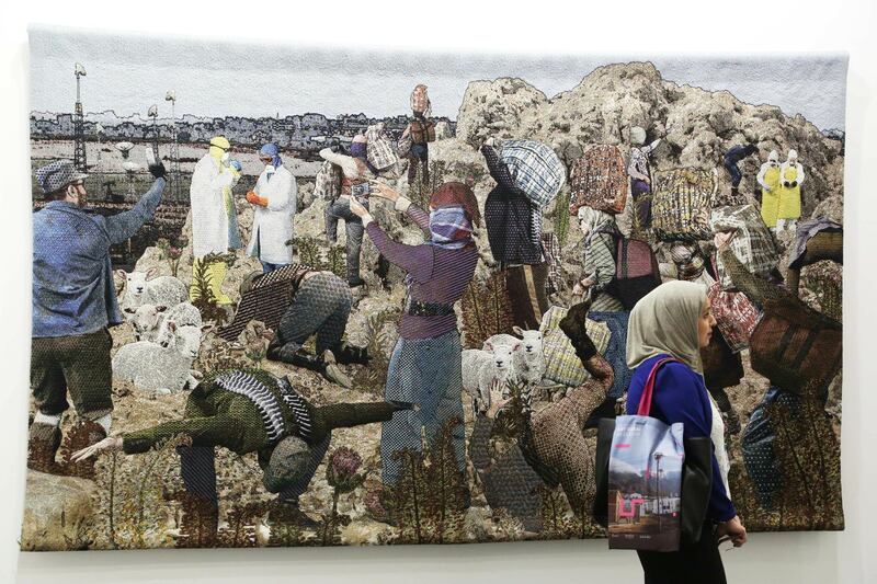 A woman walks past a 2017 work made of cotton and wool by artists Anthony Aziz and Samuel Cucher called "The Road" at Art Dubai in Dubai. AP Photo