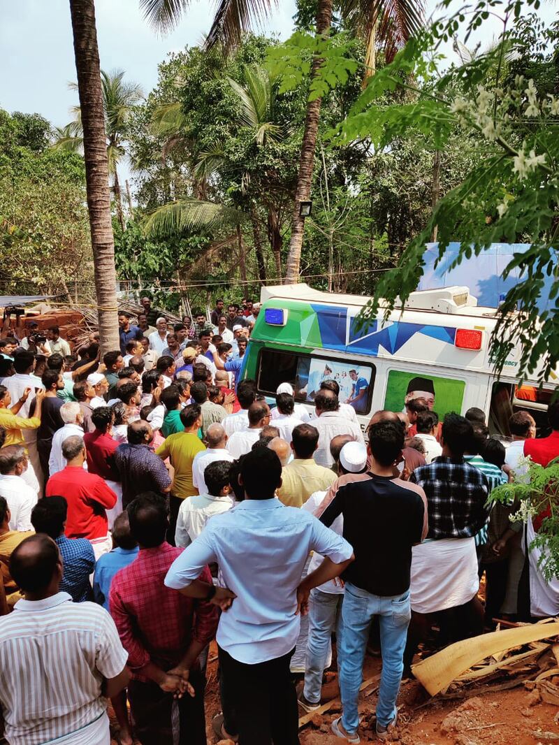 Mourners gather around an ambulance carrying the bodies. Photo: Kalangadan and Kandamangalath family